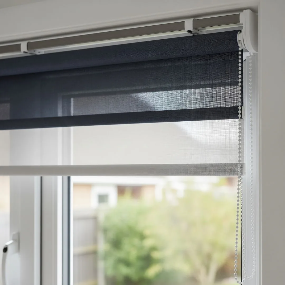 Double roller blinds installed on a window in a Bengaluru home, with a light mesh fabric partially covering the window and a darker solid fabric above.