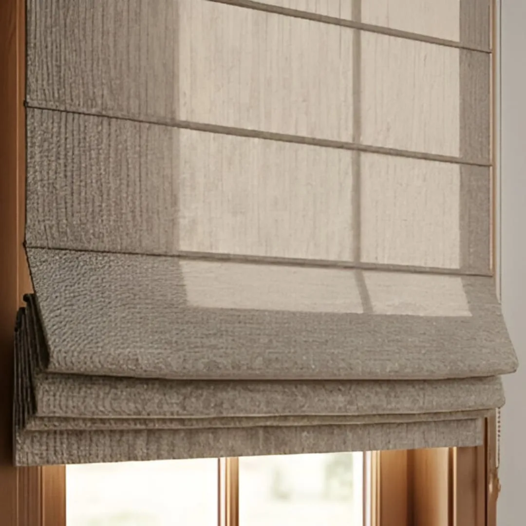 A close-up of a classic fold Roman blind with a warm, textured fabric. The blind is fully lowered, showing the soft, deep folds and layered look that adds sophistication to the room.