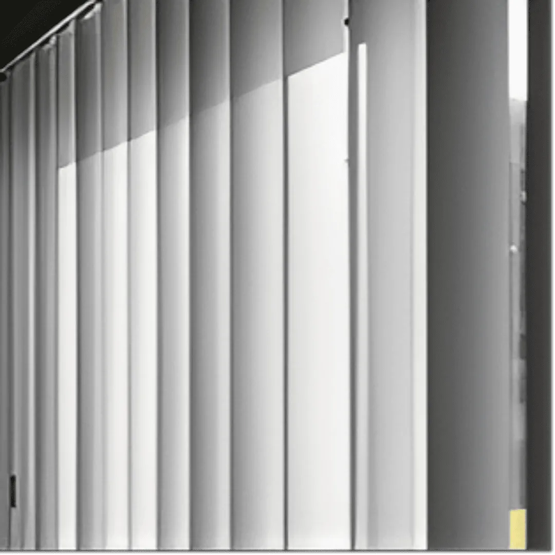 A close-up, eye-level shot of white PVC vertical blinds, partially open, with sunlight streaming through them from the left side. The individual slats are slightly angled, creating alternating strips of light and shadow. 