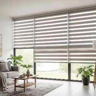 A bright living room with large windows covered in cordless zebra blinds. The blinds are a light grey and white striped pattern, providing a clean, modern look without any visible cords or chains.